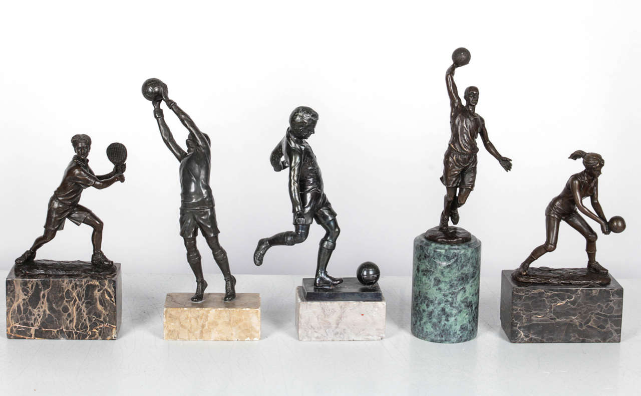 Grouping of five bronze trophies, each faceted to a marble base. One trophy is signed 