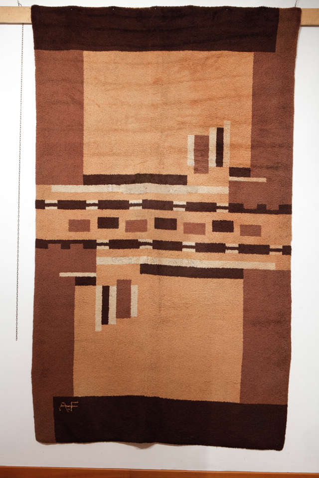 Woven in a range of shades of beige and brown, this Art Deco rug is distinguished by an abstract arrangement of intersecting planes with other geometric devices, a design that is characteristic of the carpets by Ivan da Silva Bruhns. There is an