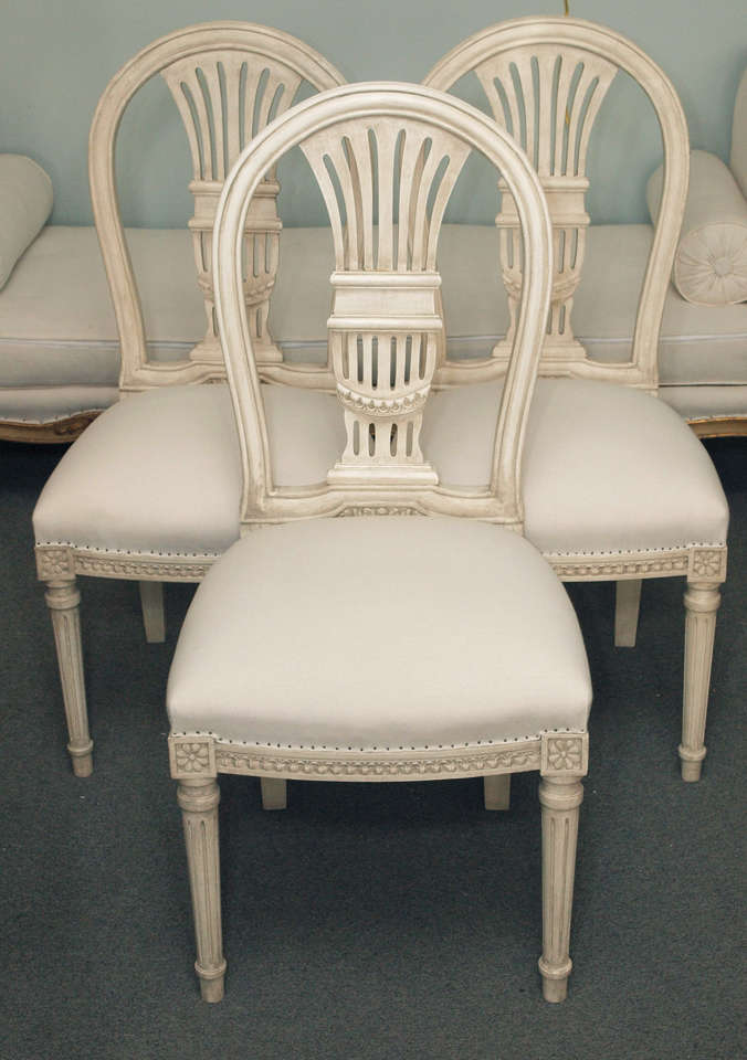 Set of 12 carved painted wood Louis XVI style Maison Jansen chairs with balloon style backs and upholstered seats. The tapering fluted circular front legs end in toupie feet.  Jansen is stamped underneath the back seat rail. The chairs are quite