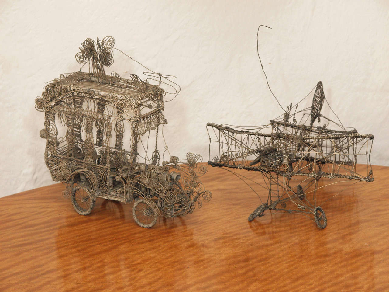 Unique and fanciful pair of wire sculptures, one in the shape of an autobus and the other in the shape of an airplane.