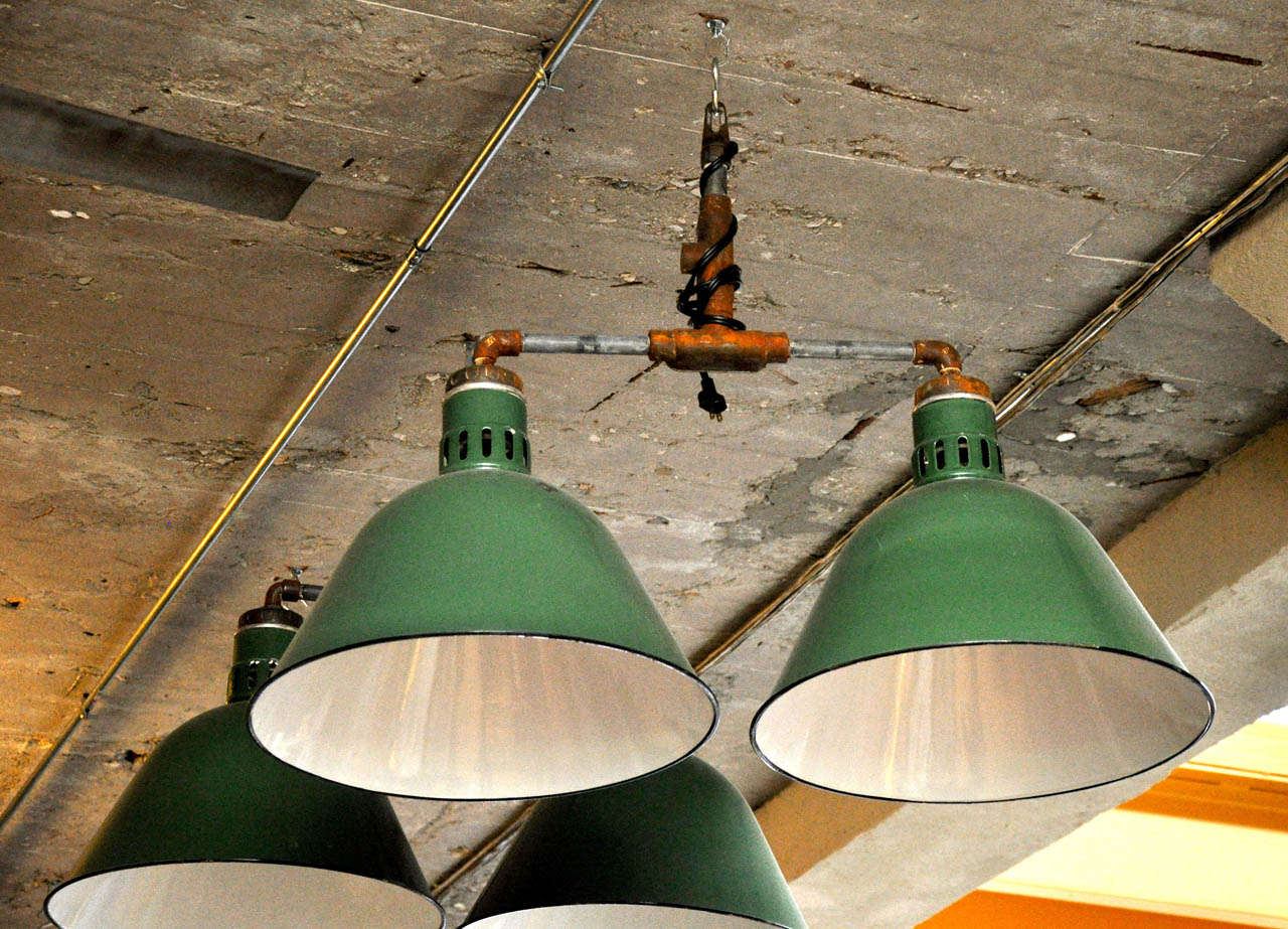 Dome shaped green and white enamel double pendant light fixtures from the mid-20th century.

Needs to be re-wired.