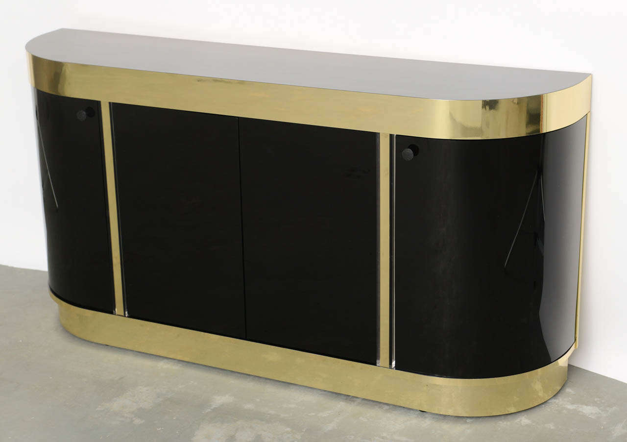 SOLD  Sleek and urbane, this slim profile console cabinet is very elegant and posh with black lucite doors, brass finished aluminum and black laminate top.  With elongated D form, this demi-lune has lucite curved side doors and center doors with