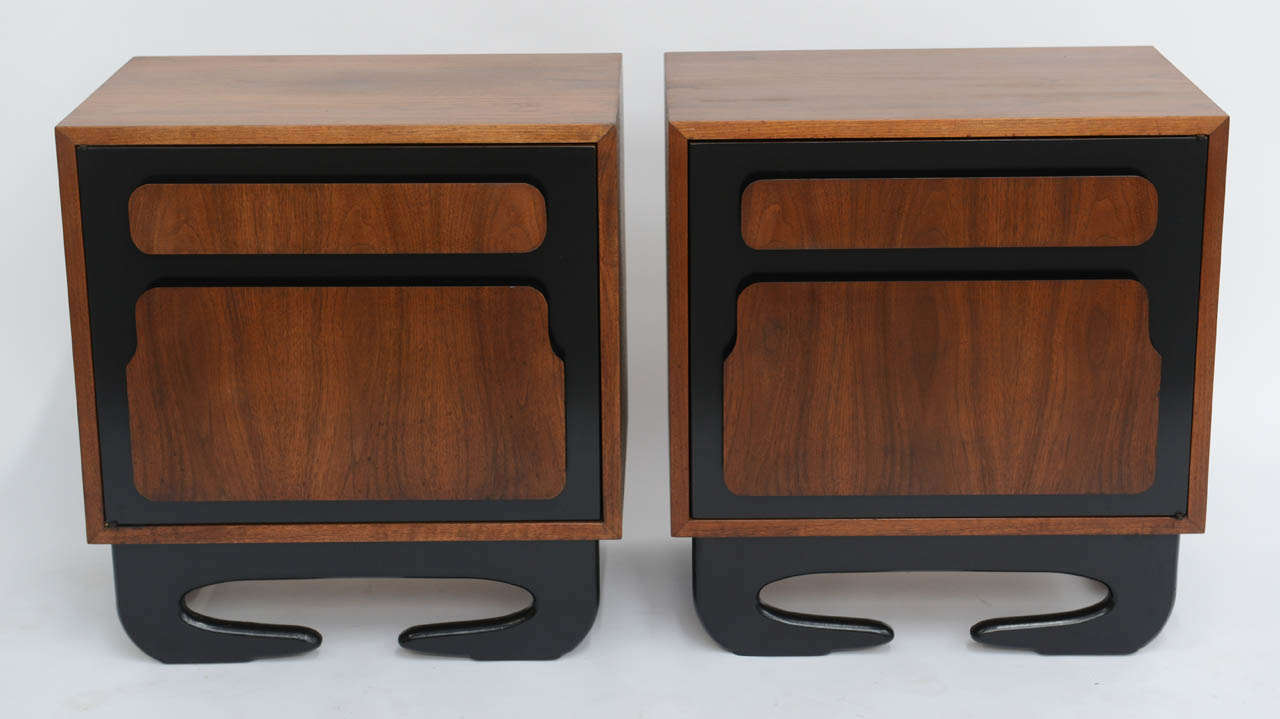Appearing to have the ability to walk, this pair of walnut night stands or end tables are unique. Beautifully figured walnut offset by black painted sculptural feet and door fronts with sculpted in relief door panels acting as pulls. Each opening to