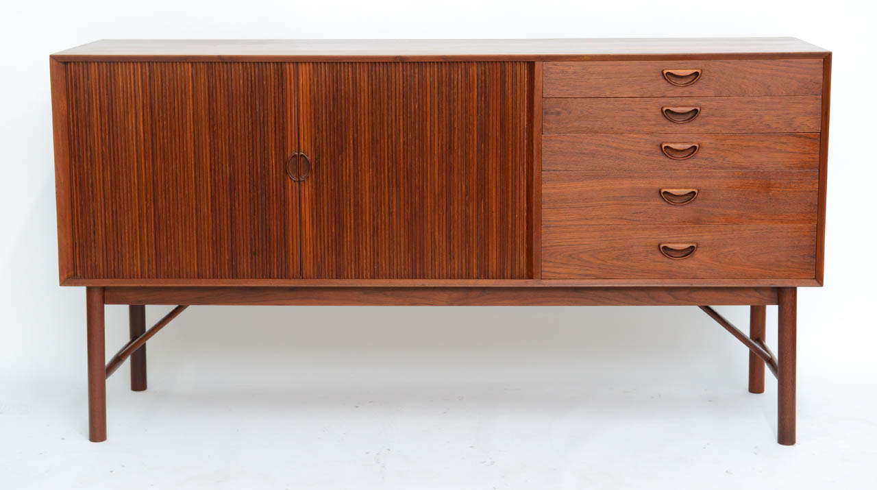 SOLD Iconic design from Peter Hvidt and Orla Molgaard-Nielsen in rich warm teak.  Master craftsmanship, quality.  Excellent condition.  Tambour doors opening to adjustable shelf with a bank of drawers to the right.  The top drawer divided and felt