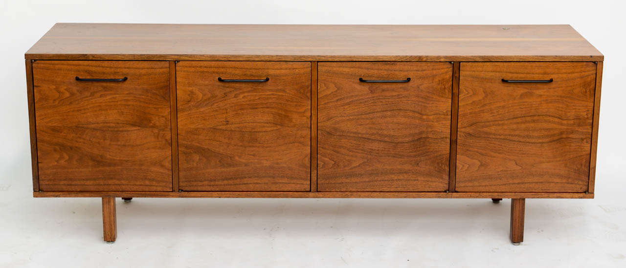 Splendid mid century modern Jens Risom credenza featuring fine figured walnut, with four doors opening to adjustable shelves. A keyed lock controlling all four doors should one want to lock. Wonderful low profile at 26