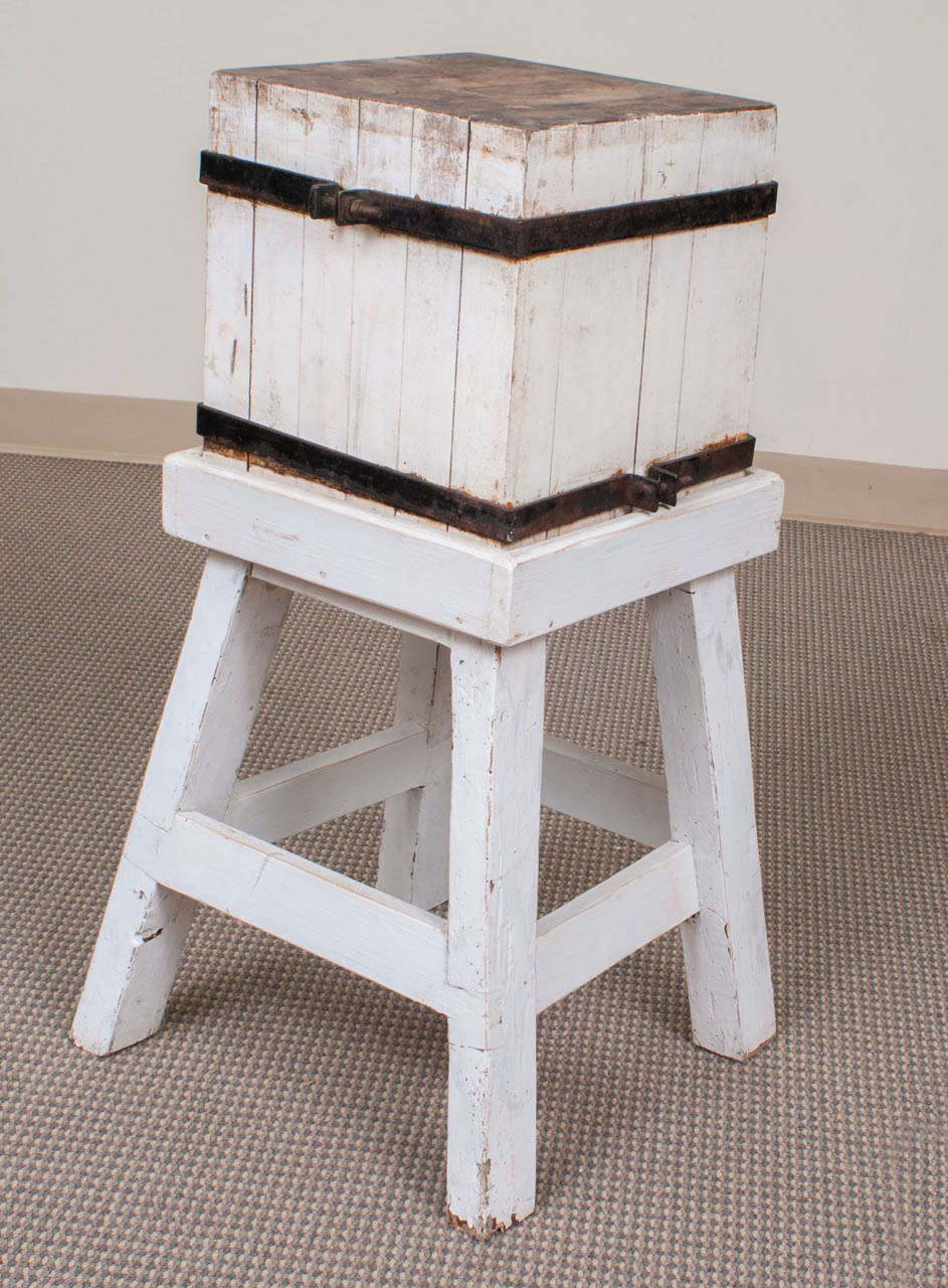A small maple chopping block with wrought iron straps on a later white-painted splayed-leg pine stand.