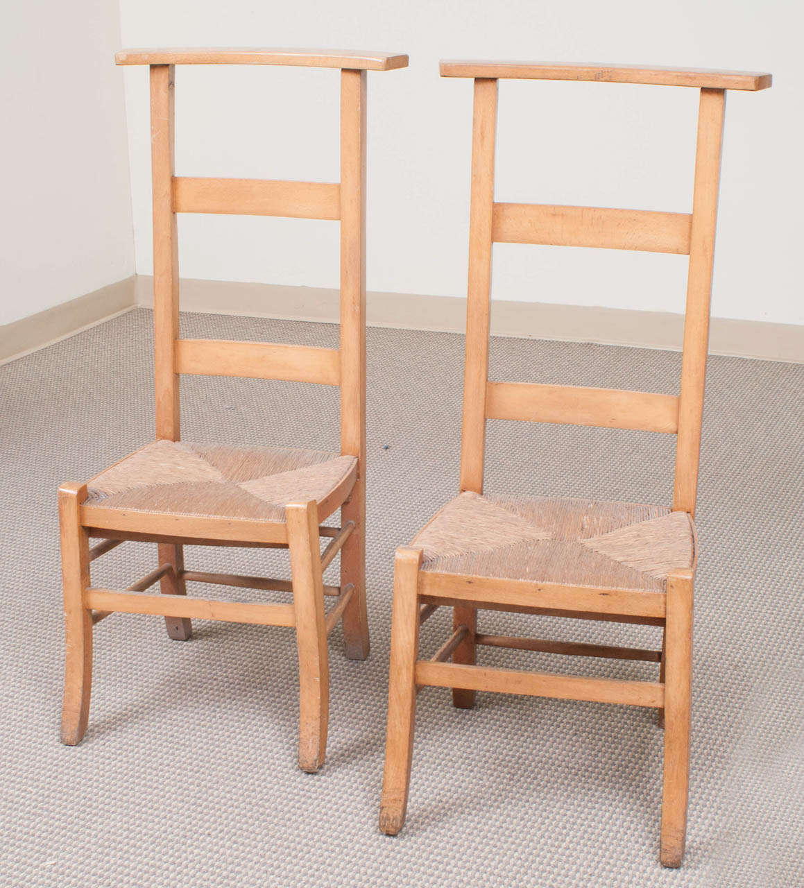 A pair of beechwood prayer chairs in exceptional condition featuring sabre legs and a woven rush seat.