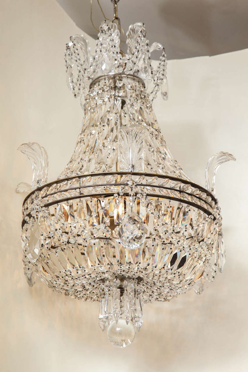 A regency style balloon shaped chandelier. The round frame inset with crystal beads forming wreath and issuing crystal leaves, the upper and lower section formed by strands of graduated beads.