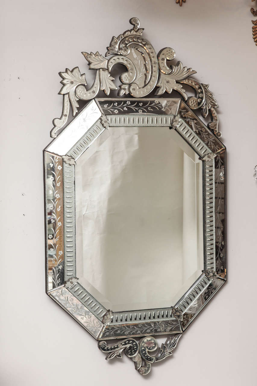 A 19th century octagonal Venetian mirror, the frame having asymmetrical crest formed by leaf and scroll motifs. The mirrored frame in sections secured by leaf shape applied ornaments, with fine detailed etched floral and leaf motifs, and having