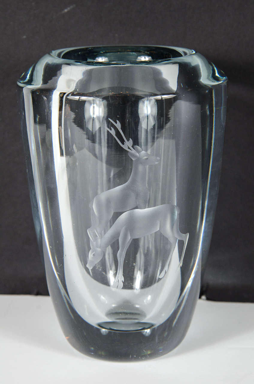 This exquisite Mid-Century Modernist vase by Stromberg features a solid, high quality blue tinted glass with a pair of deer etched into the glass. The shape is rounded, tapering down to the base, the opening also features a soft bevel. The glass is