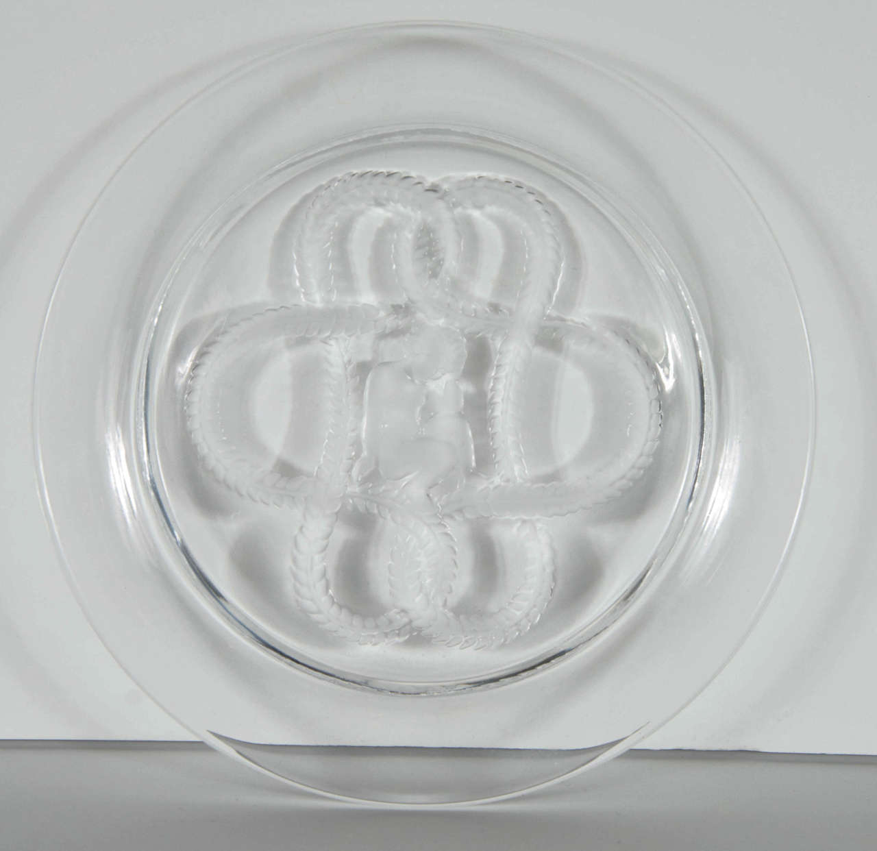 This elegant plate features a stylized interlocking laurel design and a seated cherub wearing an ivy crown in reverse etched frosted glass. This piece exhibits the meticulous detailing and quality craftsmanship for which Lalique is renowned. It