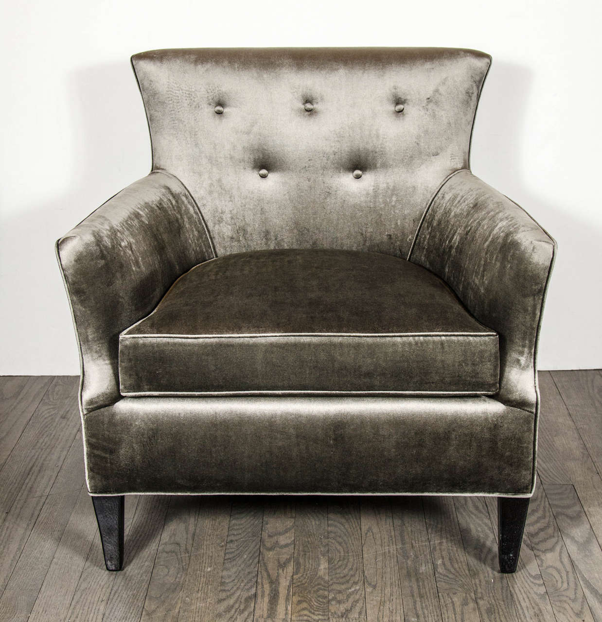 These elegant chairs feature classic mid-century design with tapered sleigh arm design and ebonized walnut legs. The chairs also feature button back detailing and are newly upholstered in smoked pewter velvet.These chairs have been restored to mint