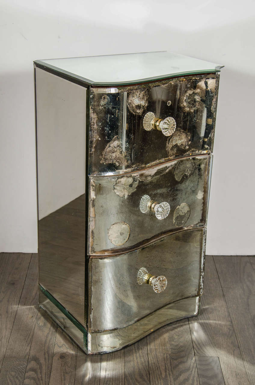 Exquisite pair of 1940's Directoire mirrored Art Deco nightstands / end tables.  This stunning pair of nightstands / end tables feature three-drawer fronts that have a Sinuous design.  The inside facing of each nightstand / end tables stands