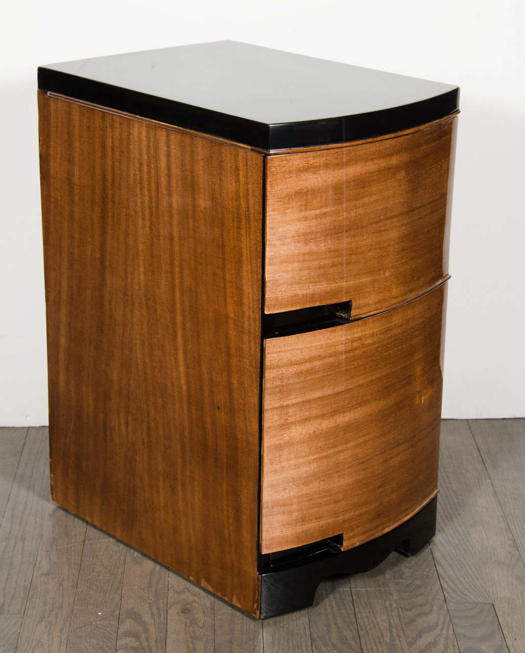 This pair of streamlined machine age Art Deco nightstands feature a bow fronted design in mahogany, two drawers groove pulls, the top and base are finished in black lacquer, and the base features a cut-out design. Restored to mint condition.