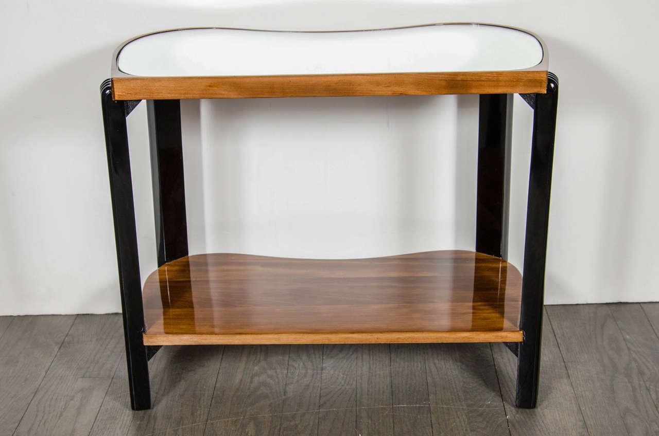 Art Deco Machine Age two-tiered side table with reeded leg design and inset mirrored top. This side tables features a bottom tier in book-matched Walnut and the top tier having an inset mirrored top while being framed in book-matched Walnut with