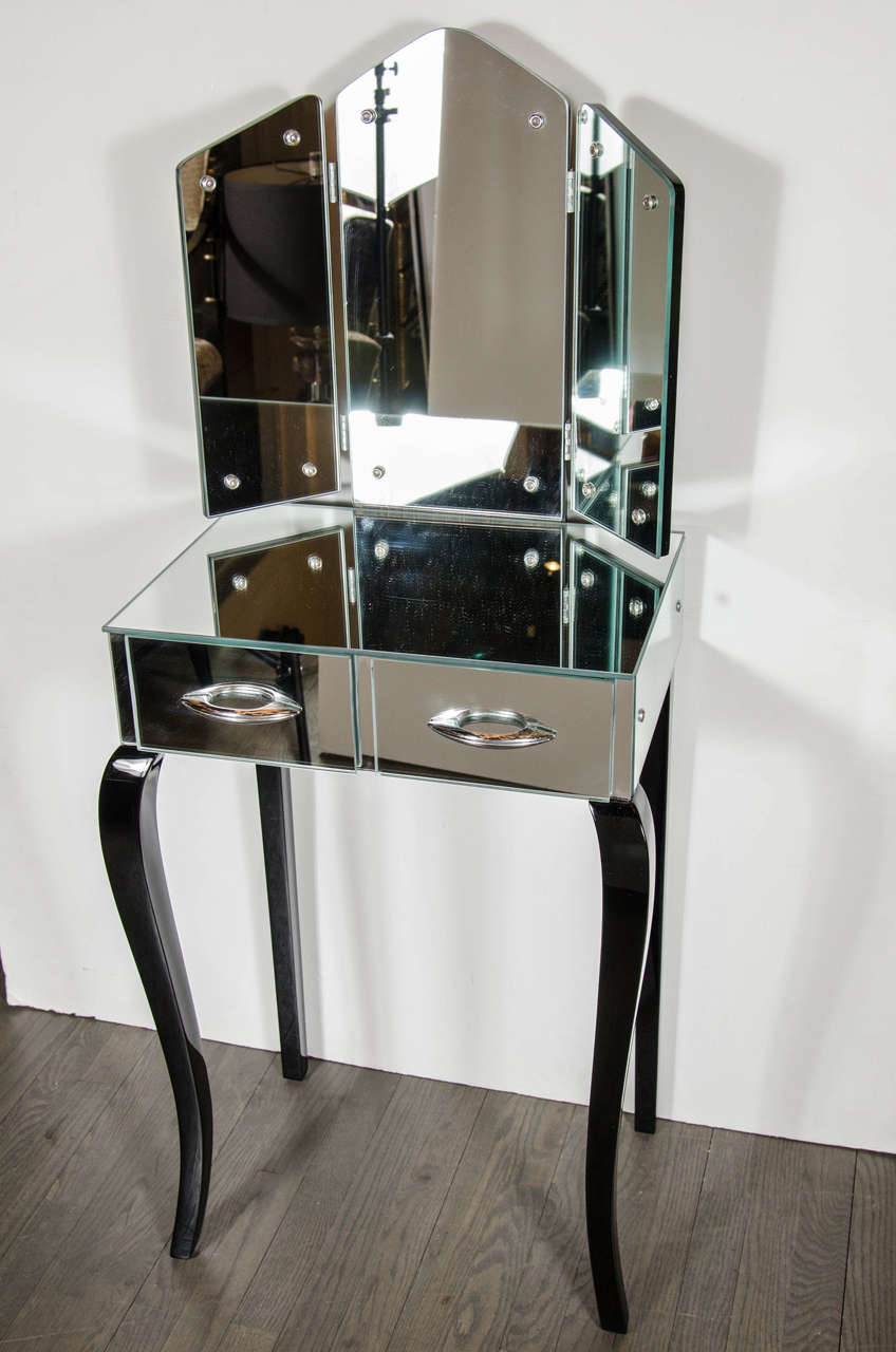 This gorgeous mirrored vanity comes complete with two drawers with chrome pulls, a demountable tri-fold mirror that enables the user to see a 180 degree view and ebonized walnut legs with plenty of space for a chic matching stool Restored to mint