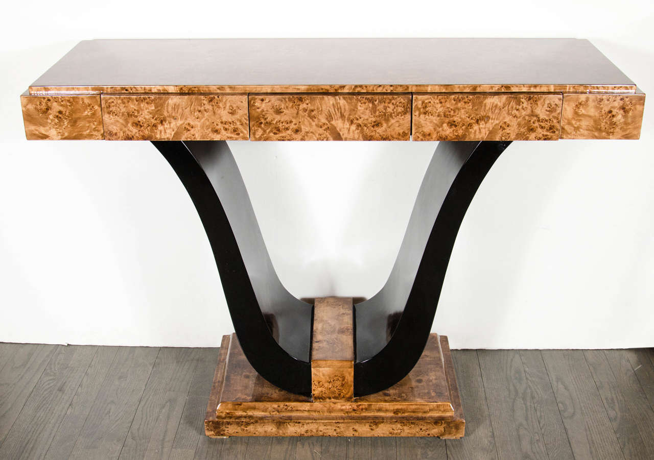 This stunning console features a U form support on a stepped skyscraper style base. It is fitted with three spacious drawers for great storage. It is made of exotic book-matched burled carpathian elm and the U form support is back lacquer. This