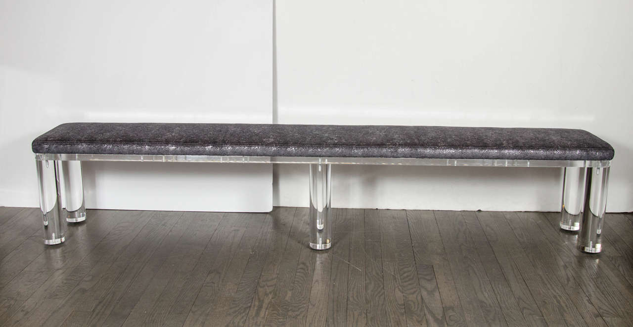 This ultra chic Mid-Century Modernist lucite bench features solid cylindrical lucite legs and textural metallic faux shagreen upholstery in a gunmetal tone. This is a great versatile piece for an entrance way or at the end of a bed. It is in