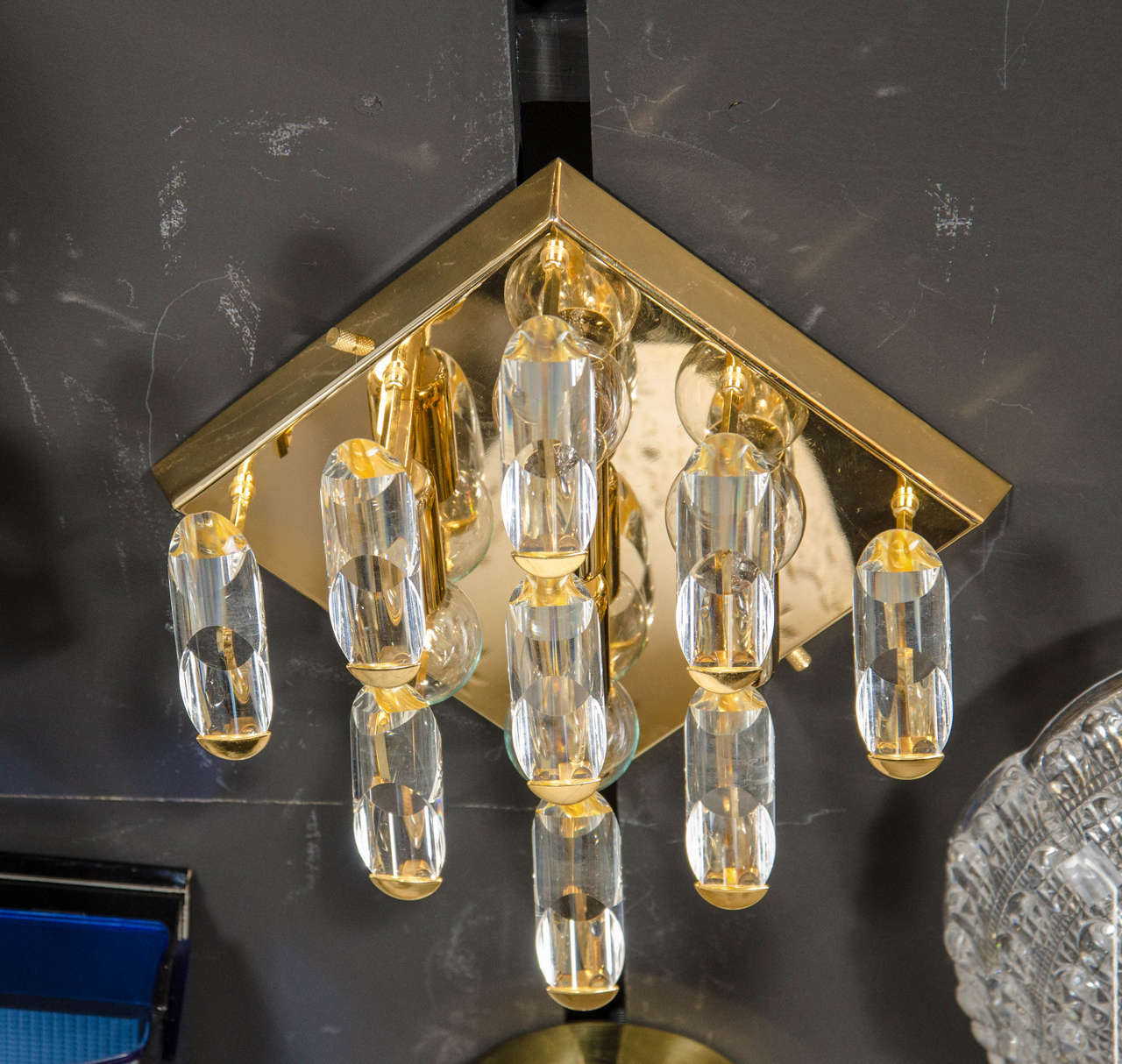 This sculptural Mid-Century Modernist flush mount chandelier by Sciolari consists of nine angle-cut pieces of lucite suspended from a polished brass square frame, the end of each piece nestles into a custom bracket holding it in parallel formation