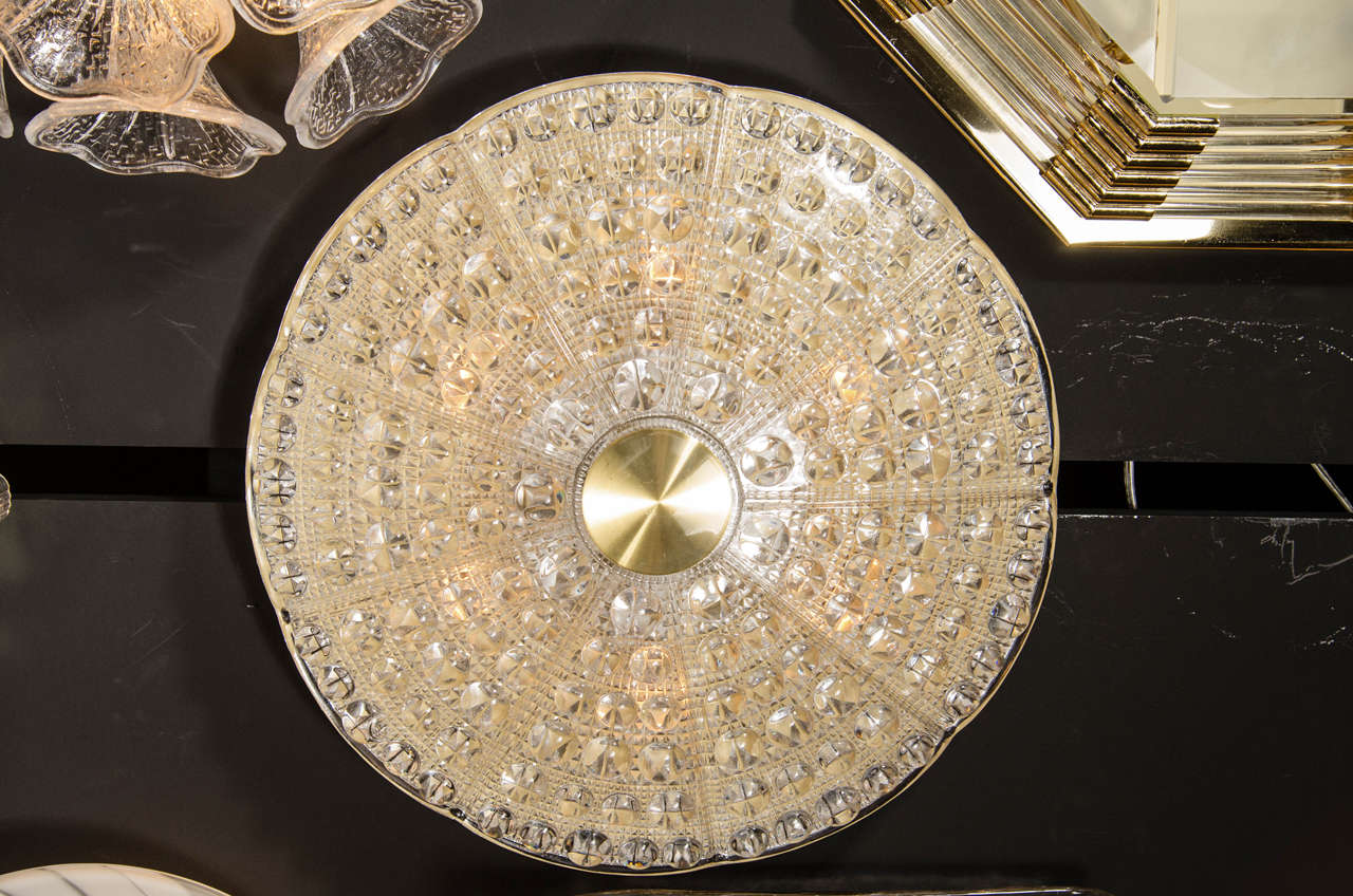 Mid-Century Modernist flush mount chandelier by Carl Fagerlund for Orrefors. This flush mount features a stunning pressed glass dome with a slight scalloped top that has accentuated lines that emanate from its brass centerpiece. The pressed glass