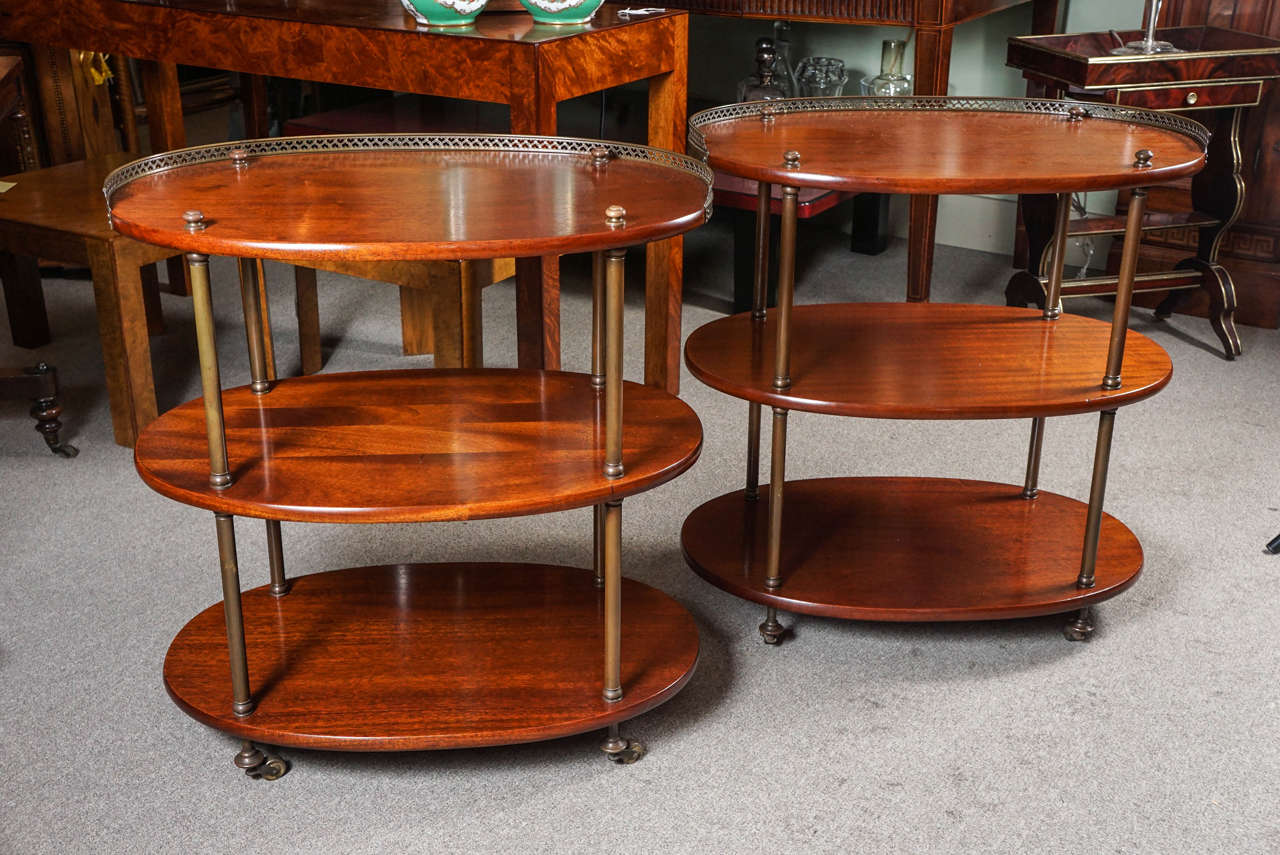 Pair of oval mahogany and brass three-tier English tables.