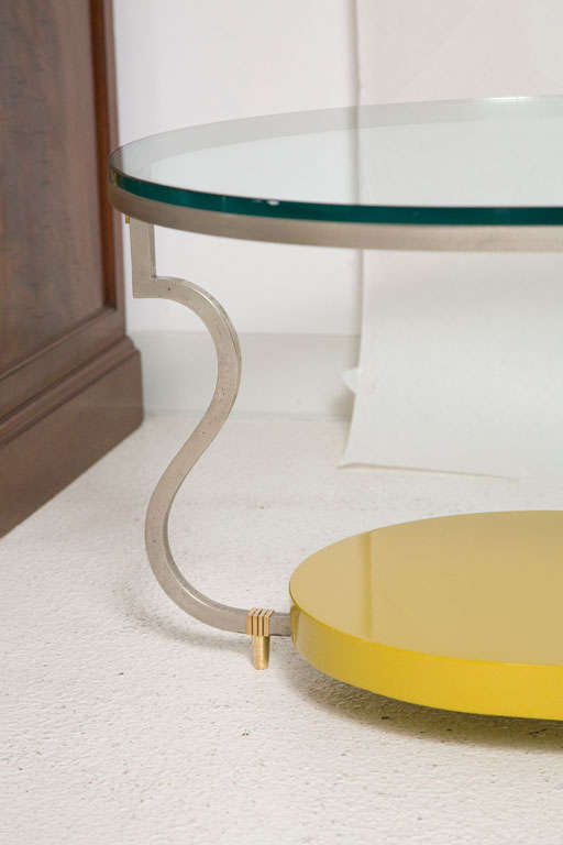 A rare stylized two-tierd race track oval cocktail table designed by Tommi Parzinger for Parzinger Originals.  This unique table is constructed in brushed steel featuring brass fittings and a 1/2 inch thick glass top.  A lacquered lower shelf