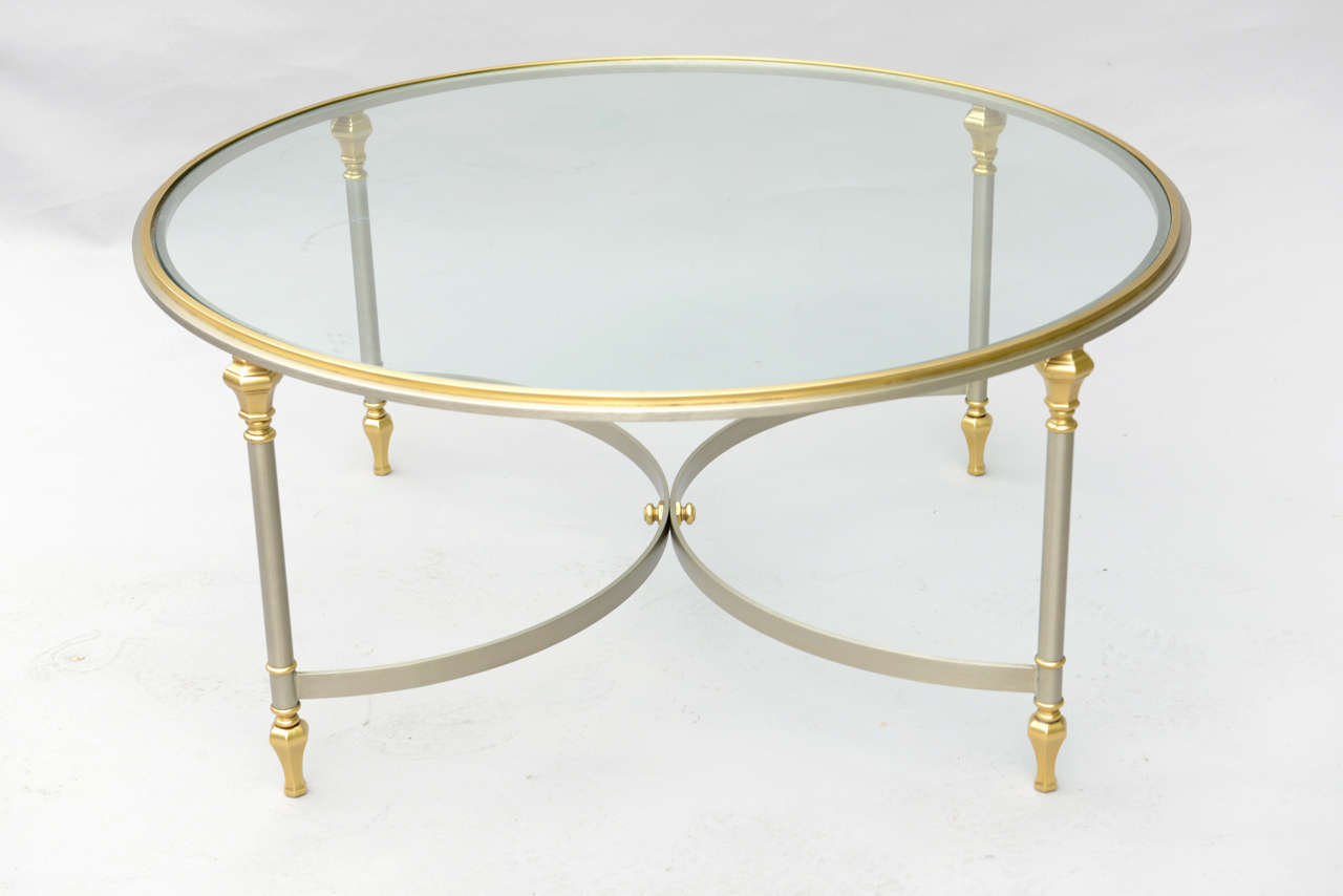 Cocktail table, having a round top of glass on base of polished steel with brass accents, raised on finial-headed round legs, joined by double-arch stretcher, terminating in stylized touipe feet.

Stock ID: D9406

(Keywords: Jansen, Coffee,