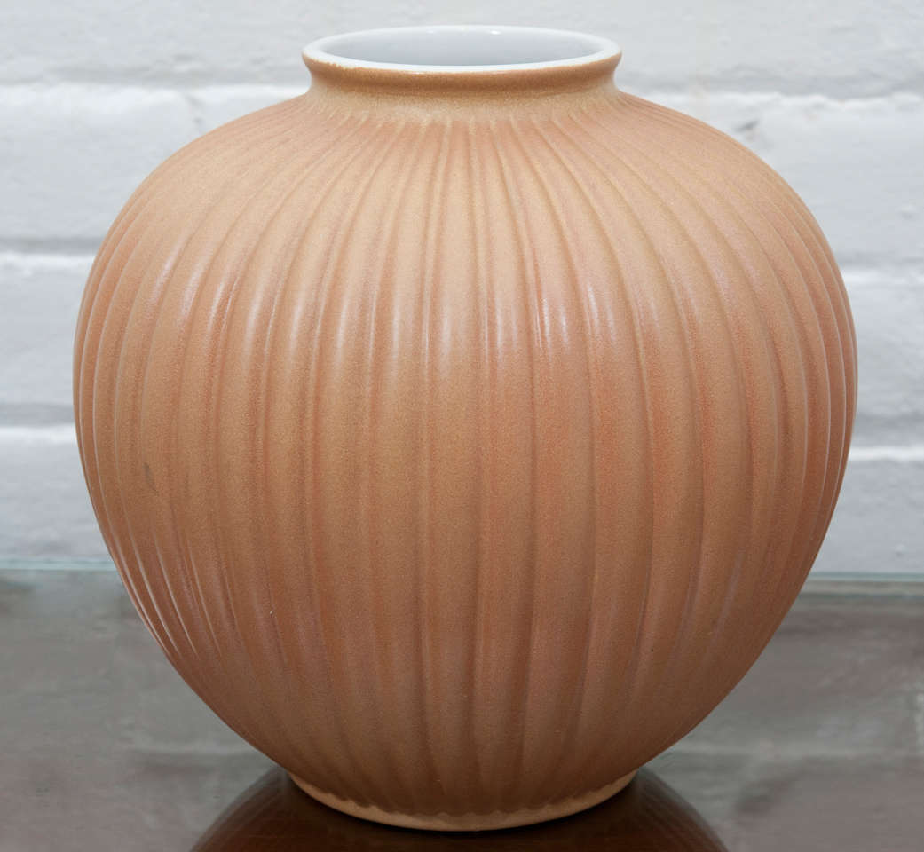 Ribbed organic shaped vase , ochre glaze with white rim and interior lining. Signed on base