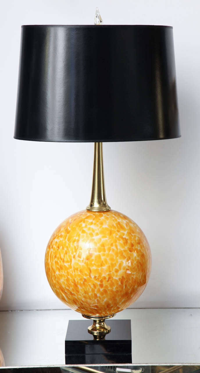 Pair of decorative Murano glass table lamps. The lamps have brass details and they sit on a black crystal glass base.