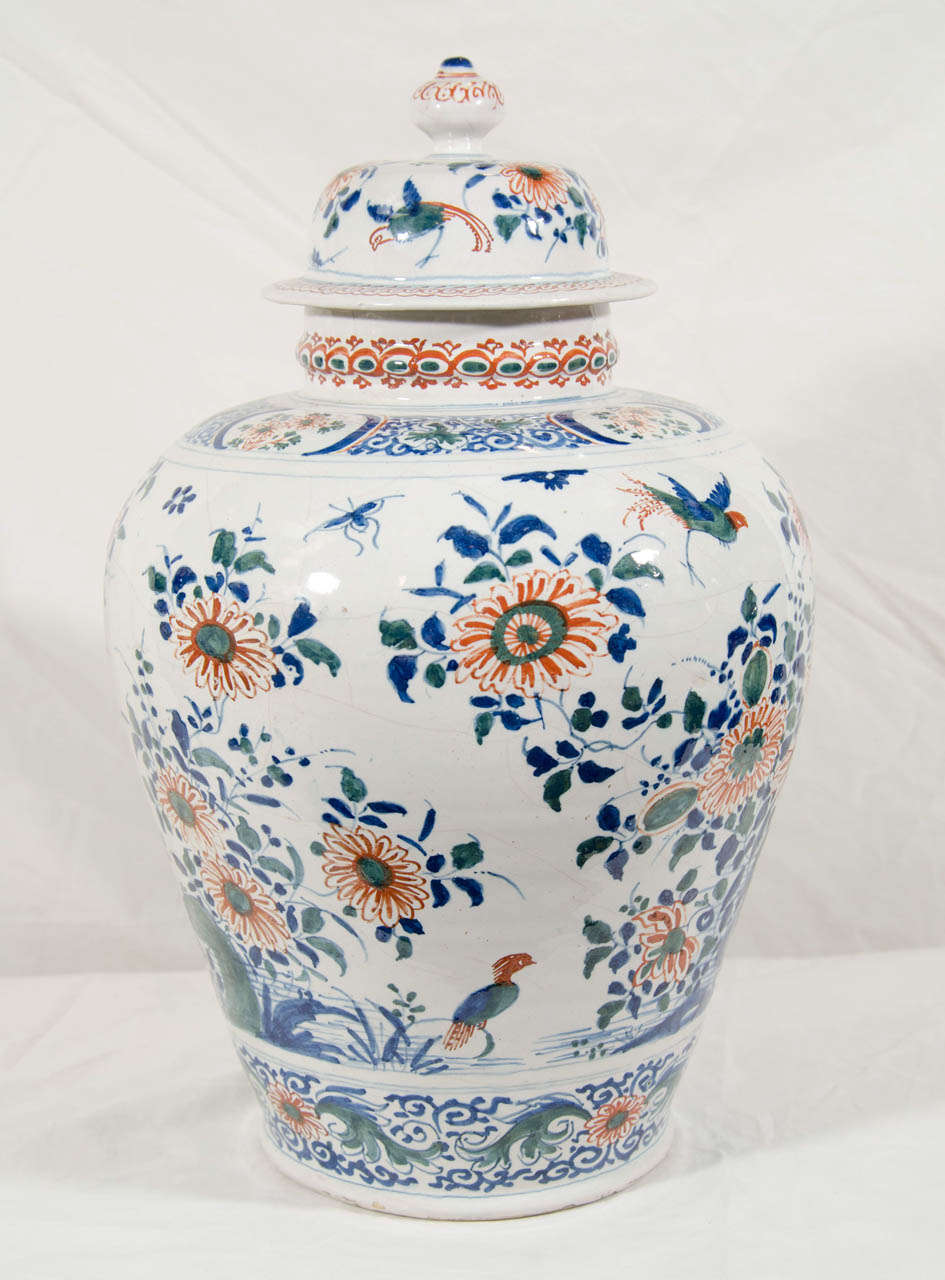 A pair of 18th century Dutch Delft polychrome vases painted in the Kashmir palette of greens, blues and oranges. The vases show an all around scene with  longtailed birds in flight and at rest in a flower filled garden.