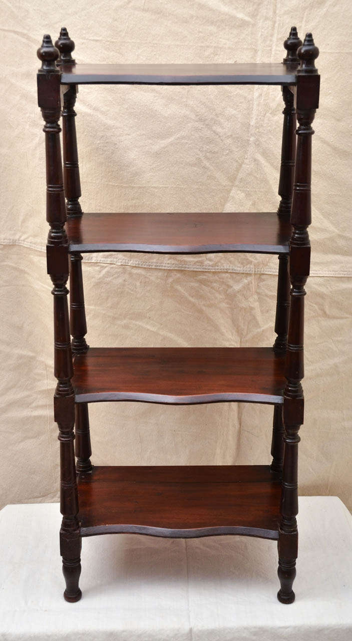 English Victorian four tier etagere with serpentine shaped shelves connected to turned corner posts toped with 4 turned finals.  Great as a bookcase or in a bathroom.