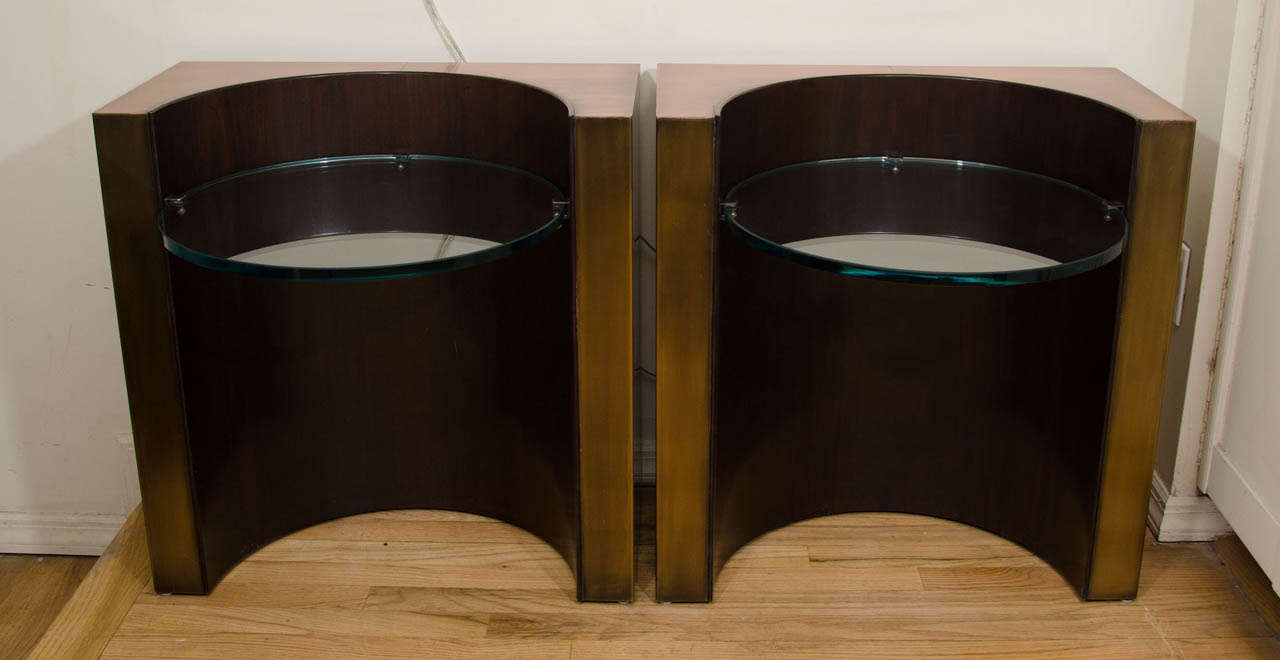 Pair of distressed brass demilune side tables with cantilevered circular glass top.