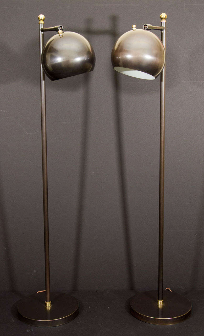 Pair of gun metal finished floor lamps with round swivel shades and brass accents.