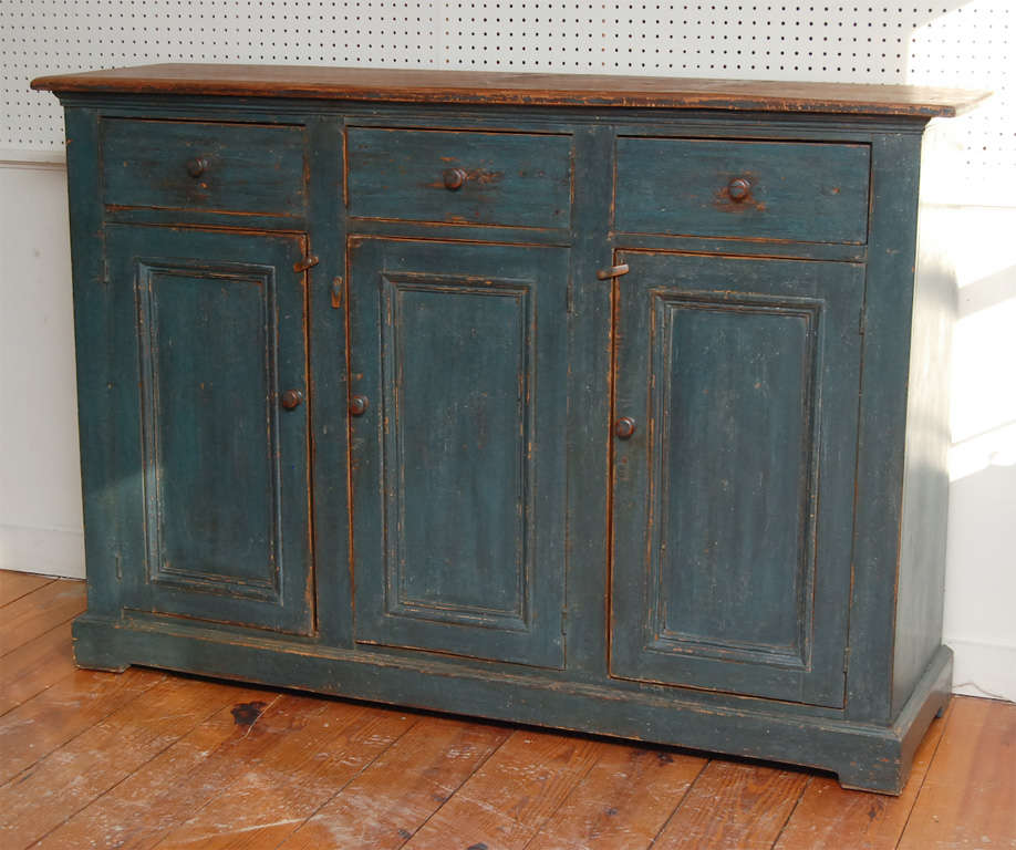 This good size early Canadian buffet is very straight forward. it has three large drawers over three tall paneled doors. Both the drawers and doors have wood pulls. there is a simple scallop low on the front and both ends. Each cupboard is divided