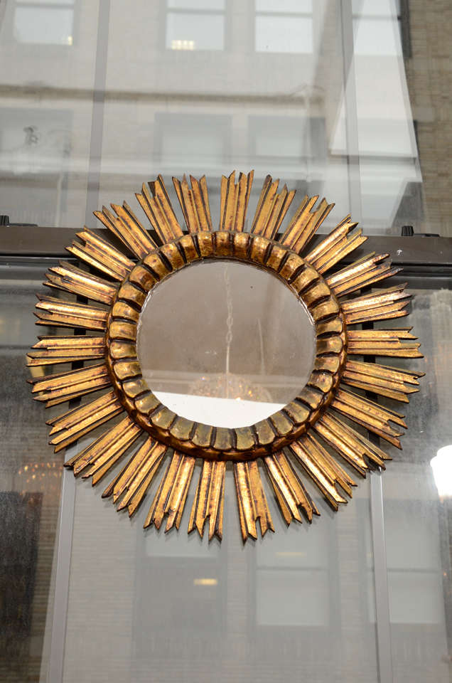 A giltwood sunburst mirror from France with molded center, mid-20th century.