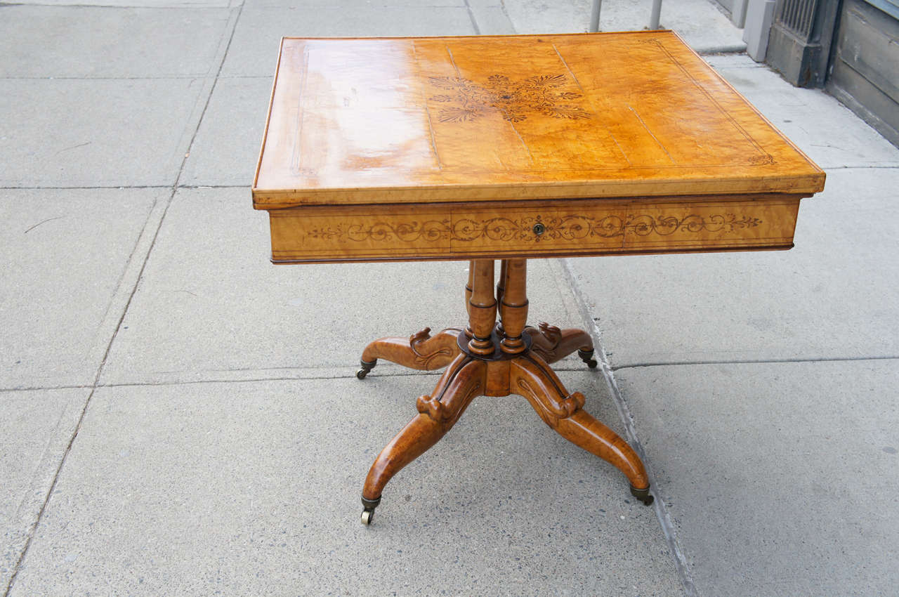 This 19th century French table made in the reign of Charles X is of an unusual form being square and  having a convertible top. The table, made from burled maple, is decorated with walnut sting inlays and solids throughout.  The top as shown is