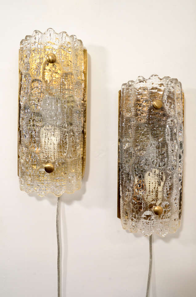 Wall sconces designed by Carl Fagerlund for Orrefors, circa 1950's - 1960's. They are made of glass and brass with a single light. 
