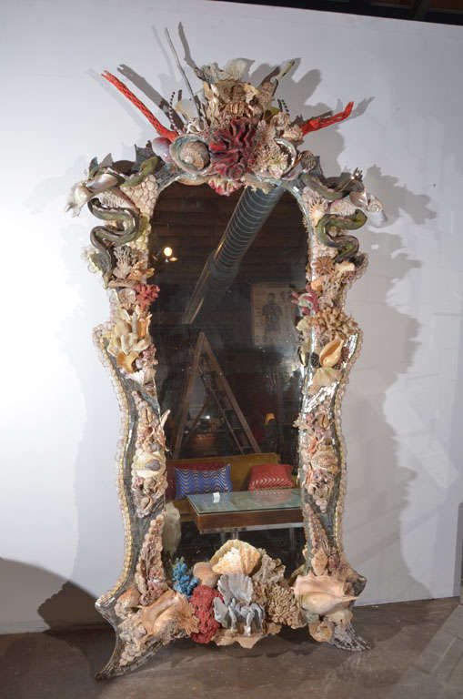 An over-the-top nod to Tony Duquette, this fabulous one of a kind mirror frame is encrusted with various sea life, real and imagined... Antique mirror fragments flow like a river over the frame, lined with blossoms of colorful barnacle and coral
