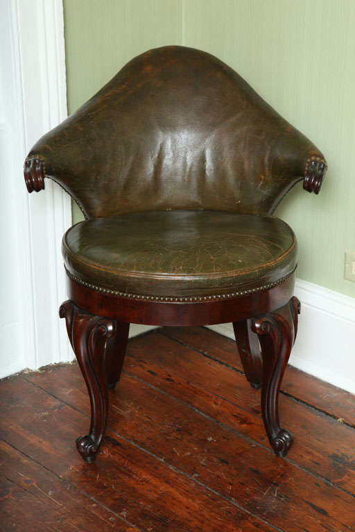 Rare antique leather and mahogany  musician's chair with low cartouche-shaped back and scroll carved arms on a balloon seat with show apron and bold front cabriole legs ending in scroll feet.  Dutch c.1840.
