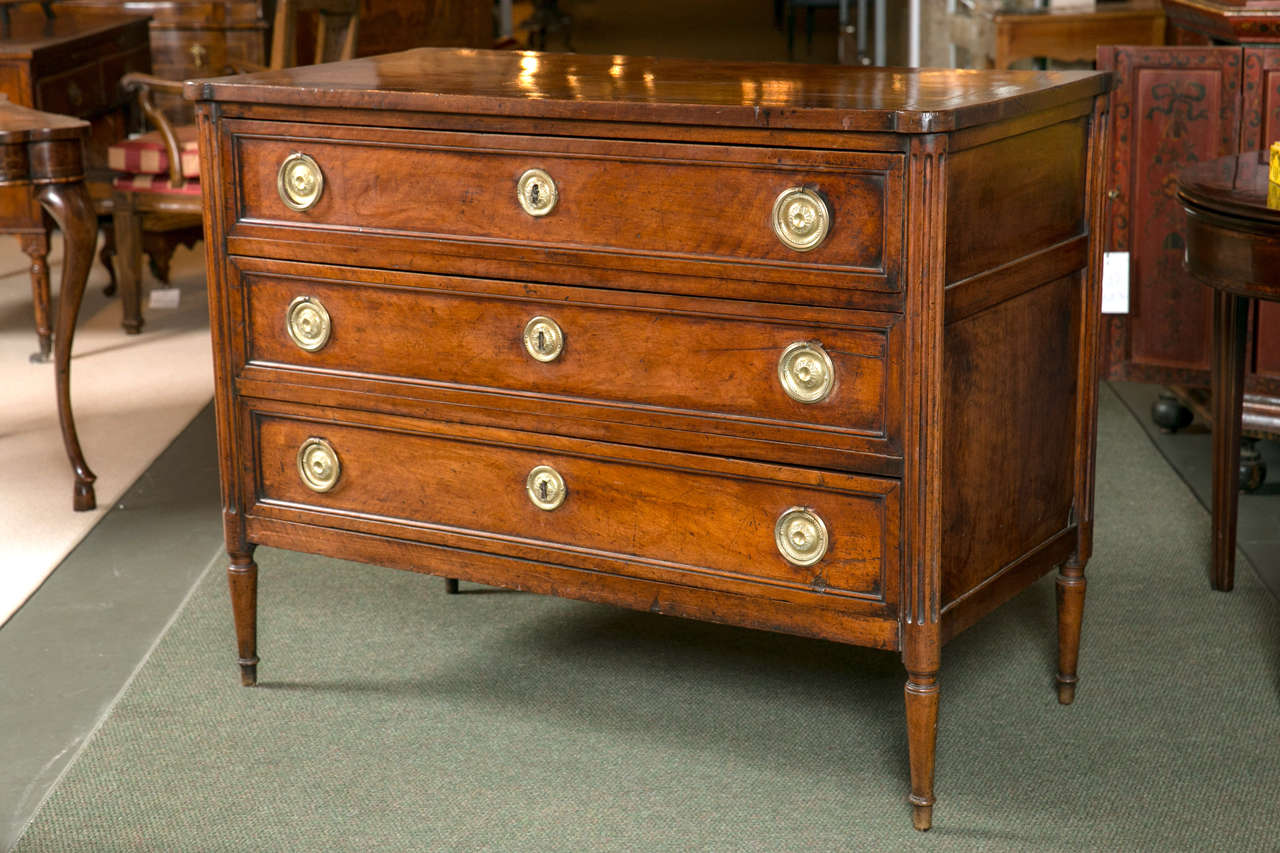 A Continental Neoclassical walnut chest of three drawers having reeded columns and ring pulls.