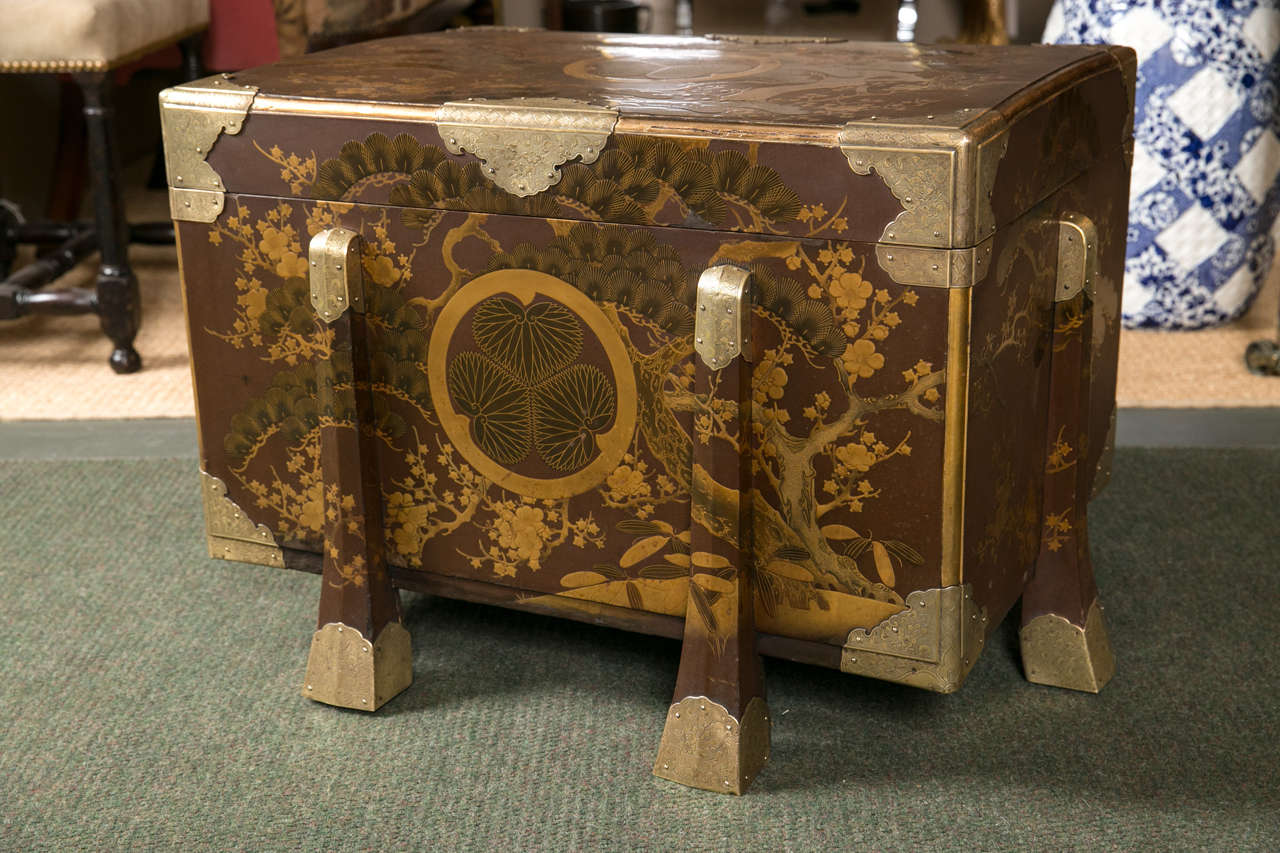 A Japanese black lacquered and gilt trunk having six legs and embossed brass trim.