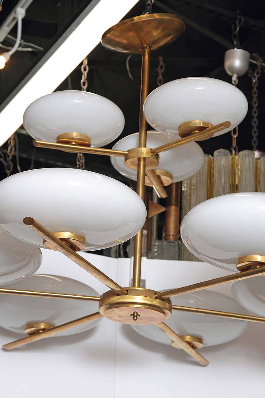 Exuberant two-tiered brass and glass chandelier in the style of Stilnovo, circa late 20th century. This large chandelier features antique brass and nine white glass bulbs.