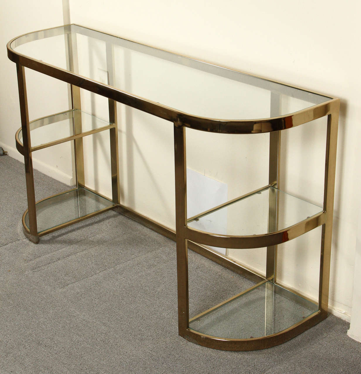 Elegant brass and glass console. This console which is brass plated and has a beautiful patina might also be used as a vanity or a small desk.