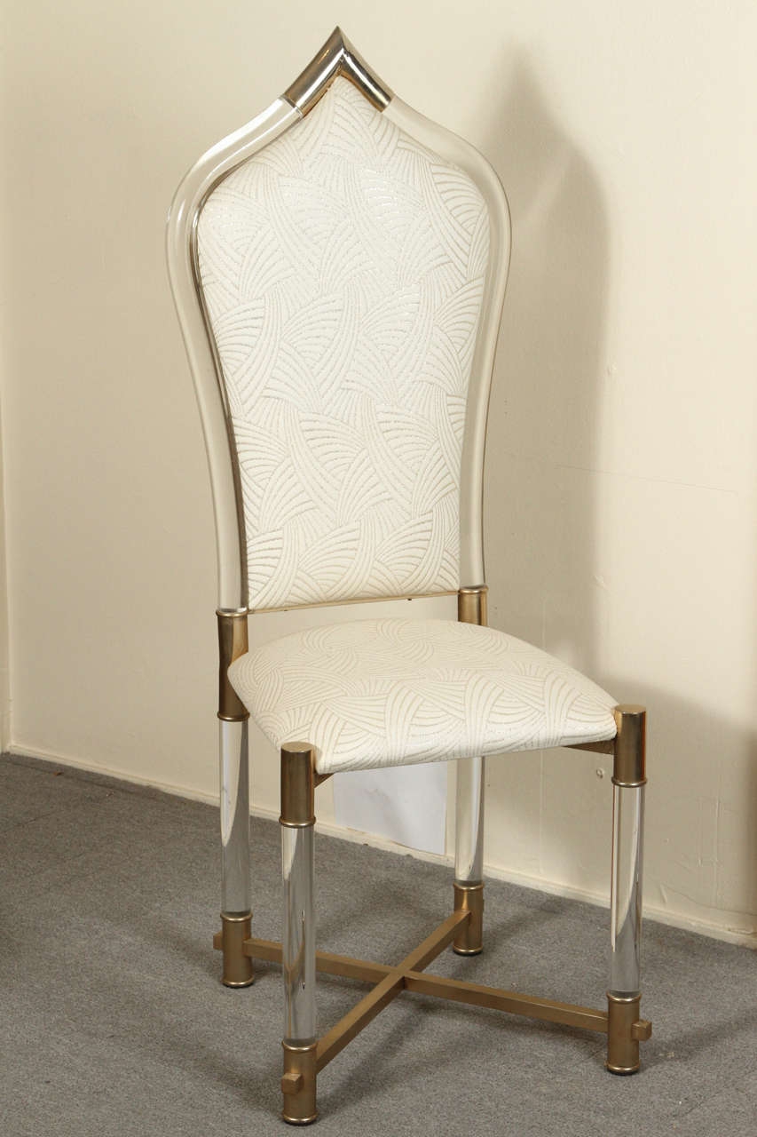 Set of eight exotic Lucite upholstered dining chairs with brass legs and trim by
Antonio Pavio.

The original fabric is white with a pattern of gold threads and is in excellent condition.