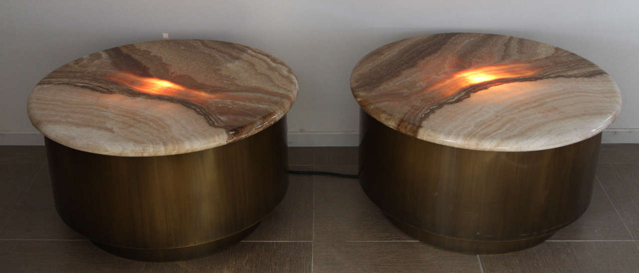 Spectacular pair of end tables by Steve Chase.
They are constructed of brass with an antique bronze brushed finish. The table tops are solid slabs of translucent onyx.

They have been provided with an interior light that gives the onyx a warm