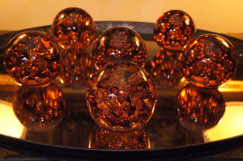 This collection of weights made in a rich deep amber color  are made by hand blowing with many trapped air bubbles for drama and movement within the glass. Each is slightly different in size and number and placement of air bubbles. Though not signed