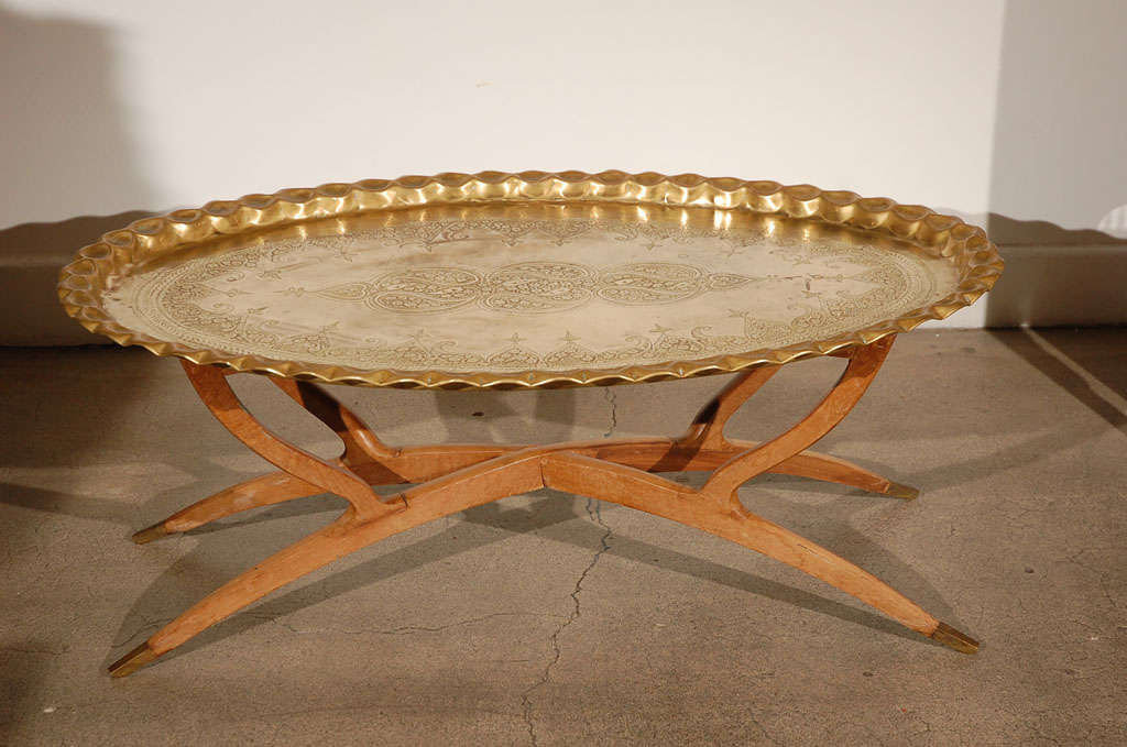 
Mid century Modern stylish large oval hand etched, hammered and embossed, chiseled Moroccan polished brass tray table on collapsing spider wooden base.
Moroccan or Middle Eastern Style Coffee or cocktail table great to use indoor or