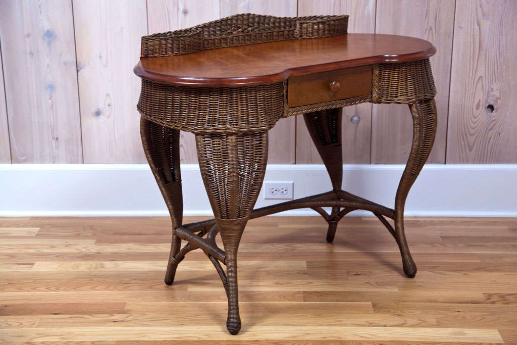 Beautiful Art Deco wicker desk with hard wood top.  Diamond pattern in woven gallery.

Dimensions:  39.5