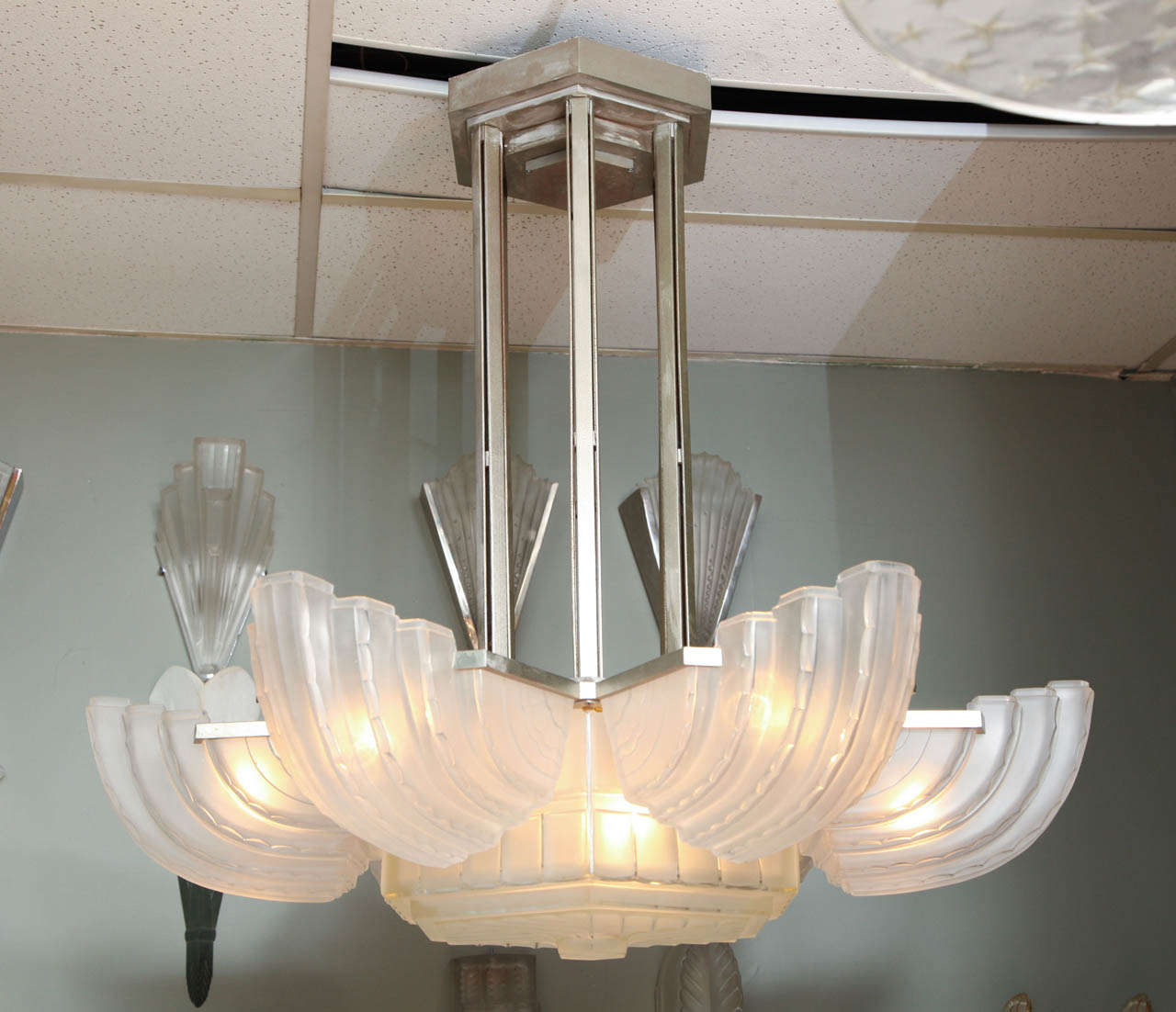 Marius Ernest Sabino. Art Deco chandelier, circa 1930, comprised of six clear and frosted glass shades radiating from a central hexag, mounted in a polished nickel brass frame. 

Measures: Diameter: 36", height: 35”.