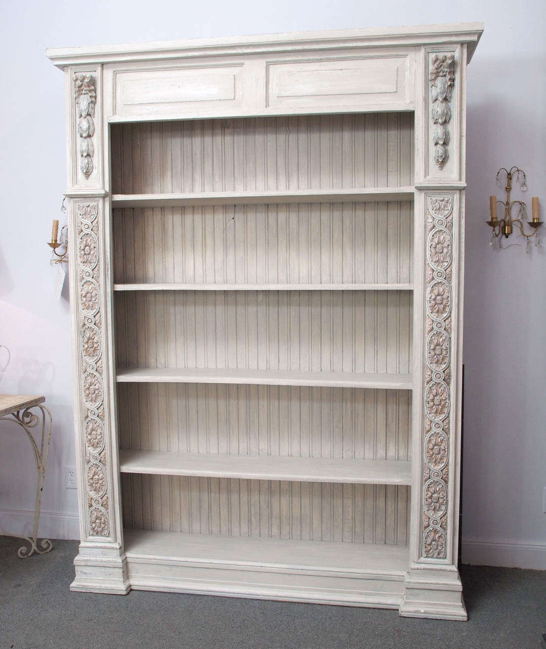 19th century Italian library case containing six shelves. Decoratively carved panels line each side; the finish, which has been updated, is distressed paint and worn gilt.